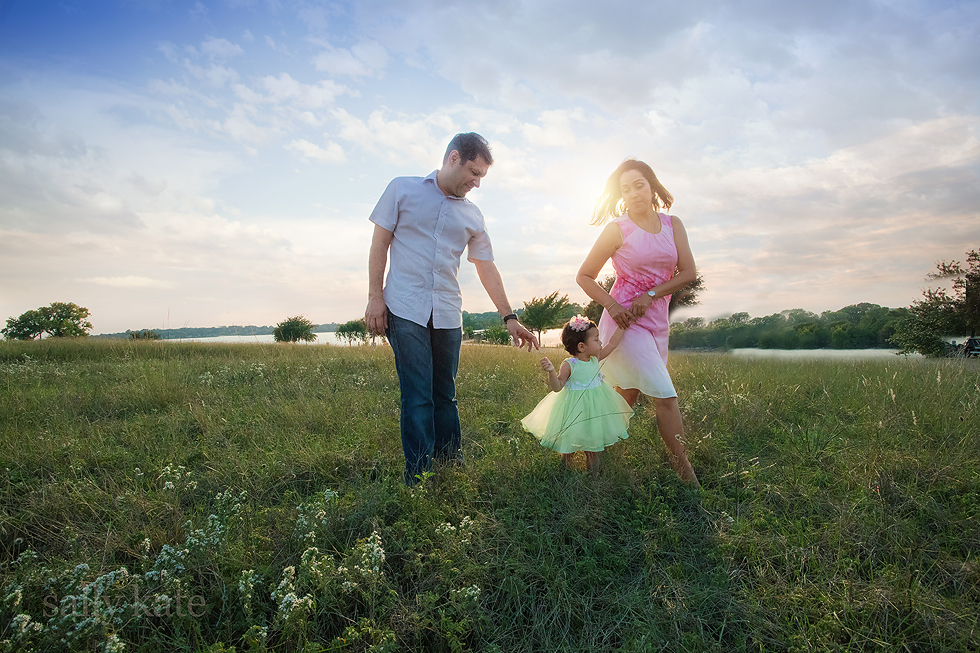 family walking on a flowered hill smiling