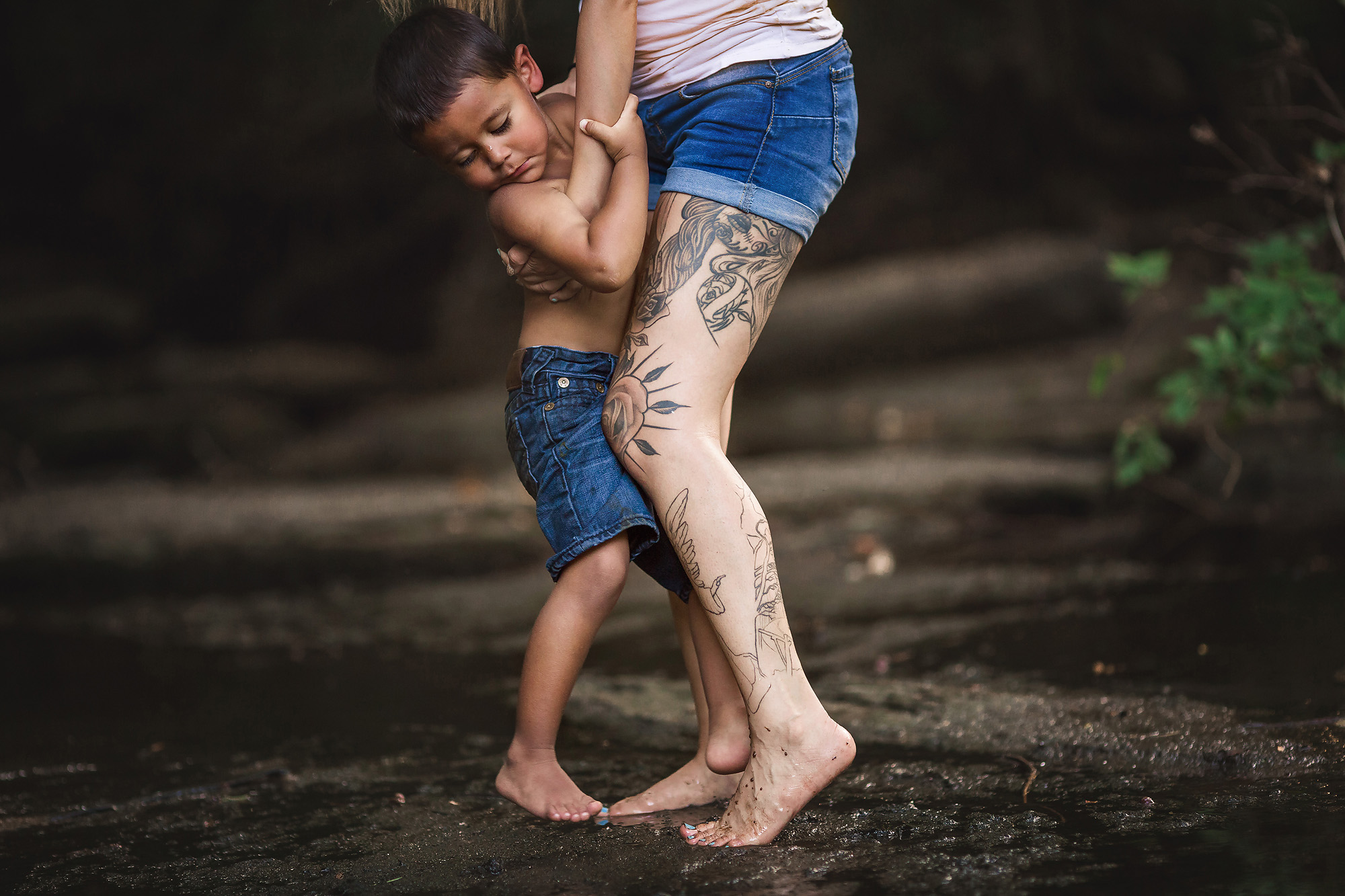boy holding on to mother at creek