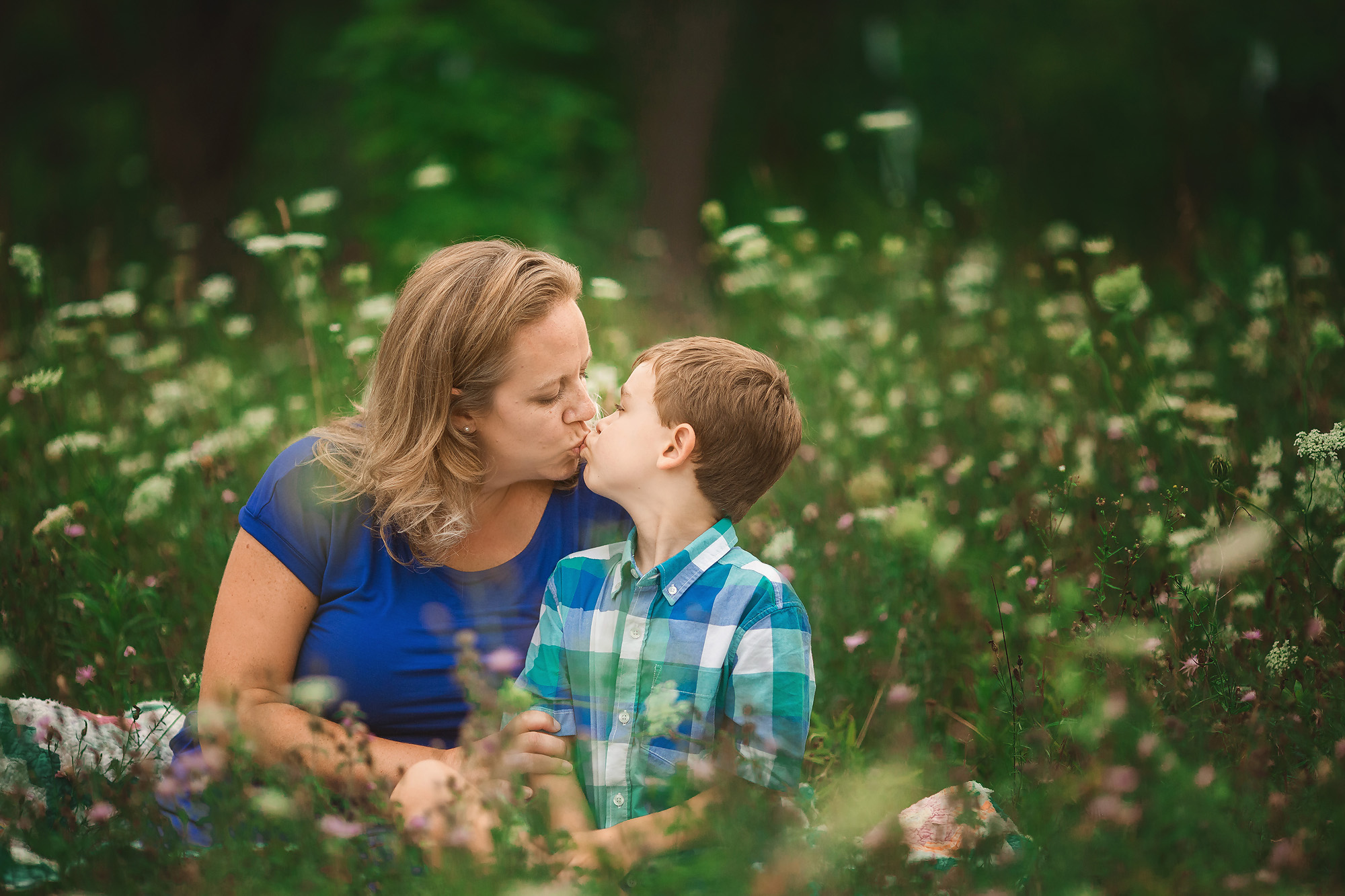 mother kissing son sitting in flowers