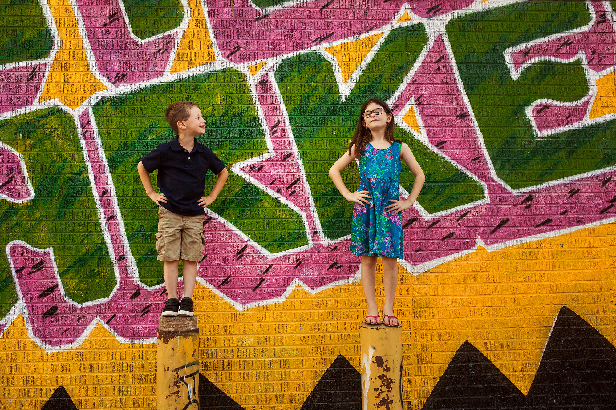 brother and sister against painted wall