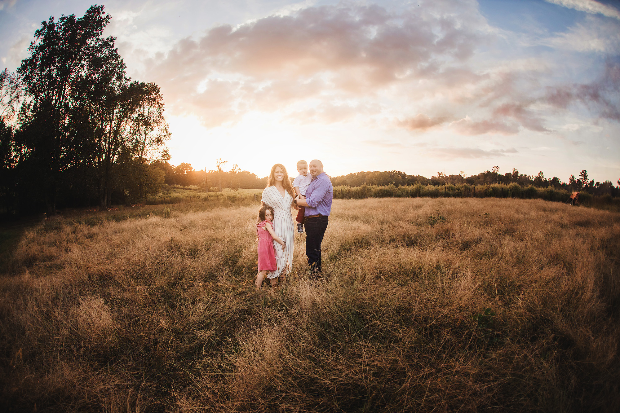 family in tall grass sunset