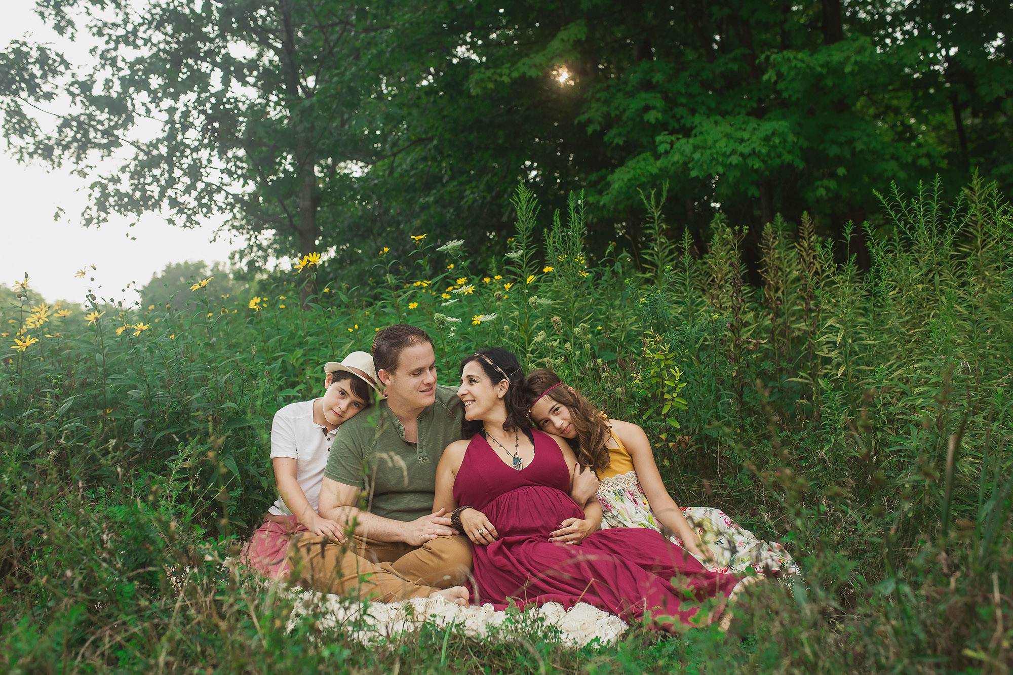 family sitting together in field of flowers
