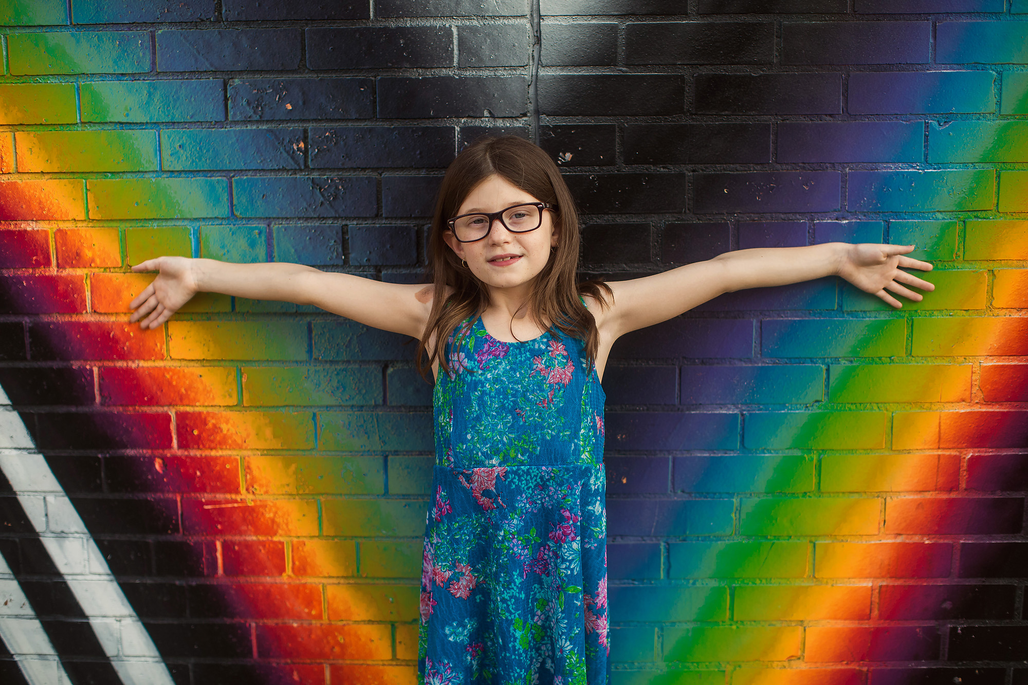 girl standing against rainbow painted wall