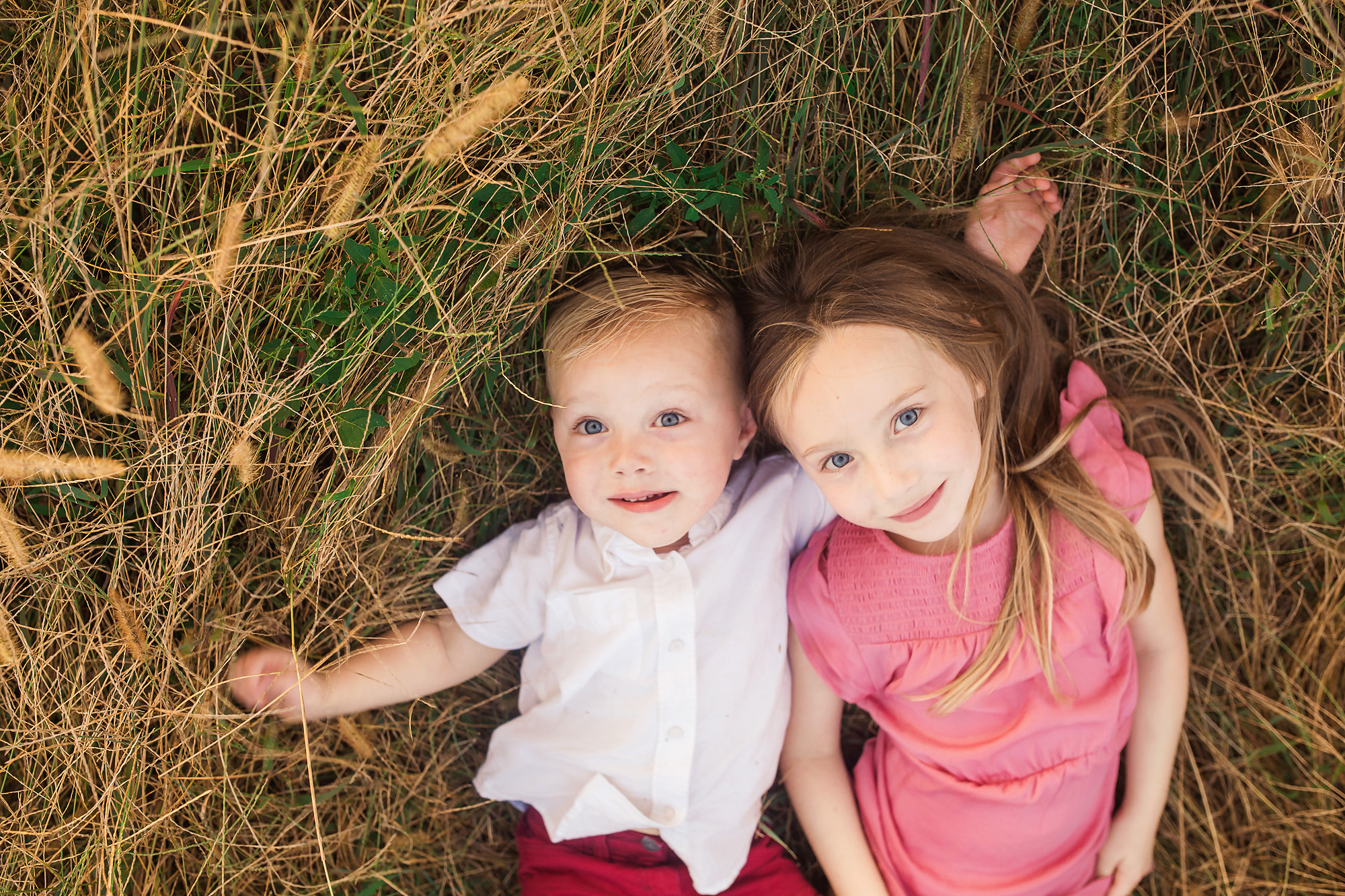 brother sister laying in grass portrait