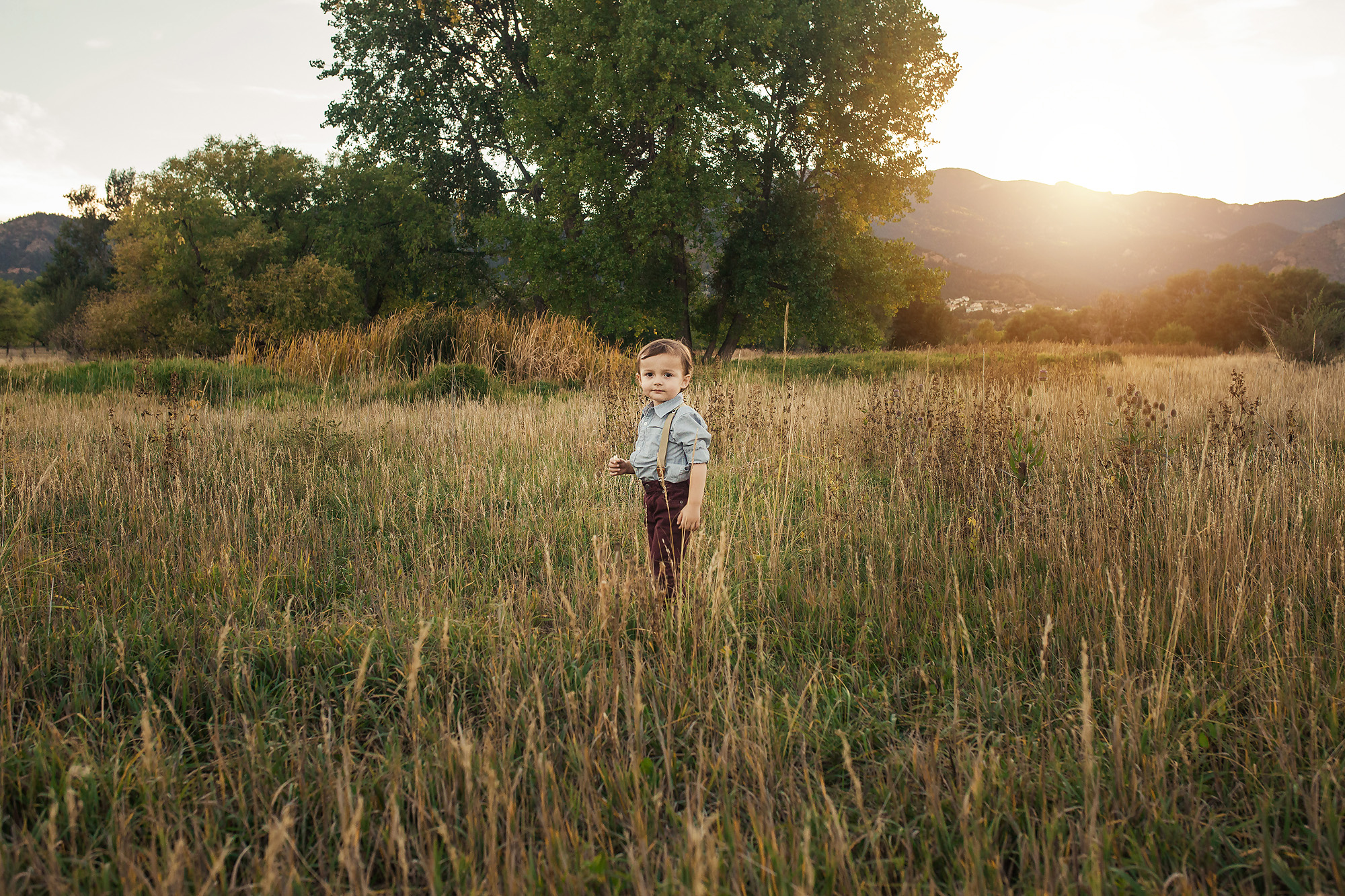 boy standing in field sunset