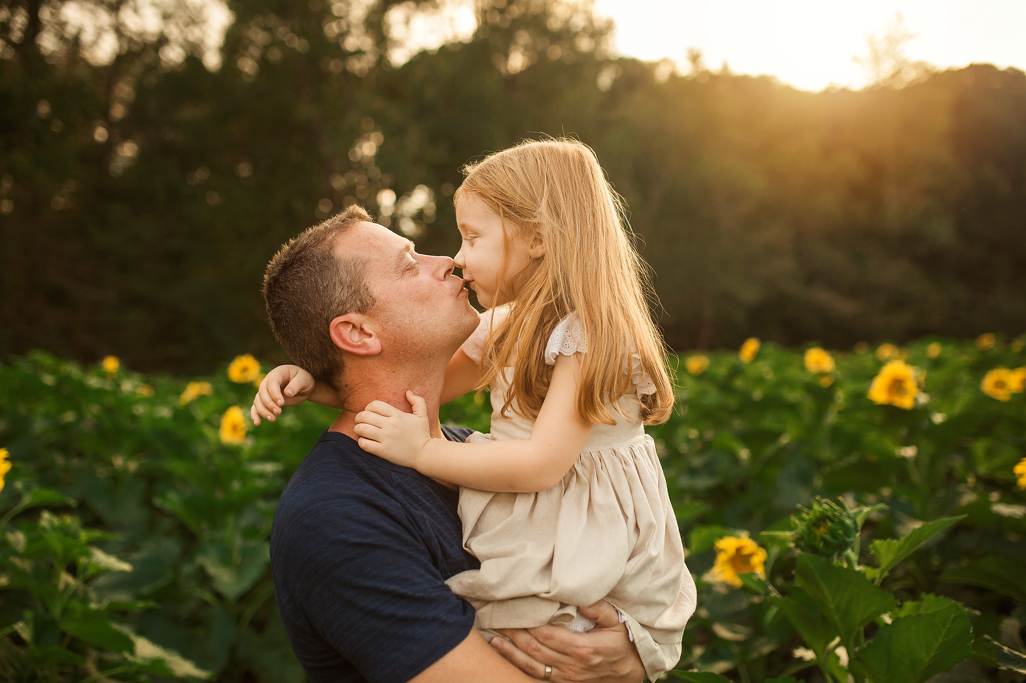 girl kissing father by sunflowers