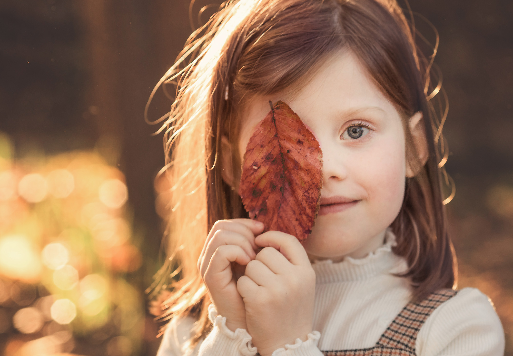 girl holding leaf over eye