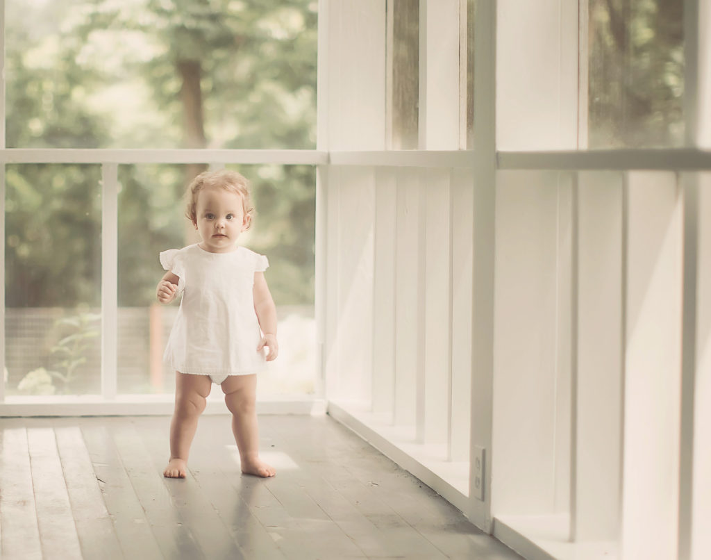 baby girl standing on porch white dress
