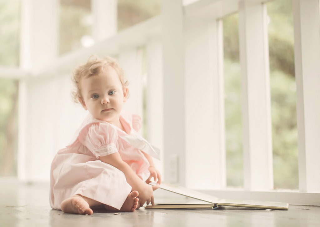 baby on floor porch with book