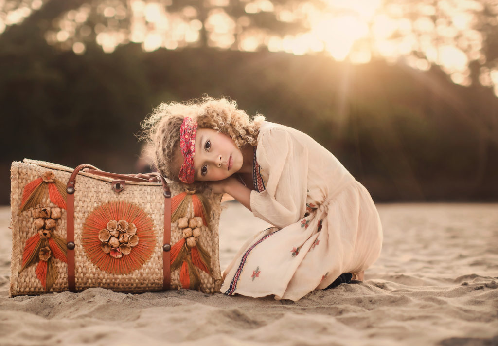 girl leaning on bag in sand portrait