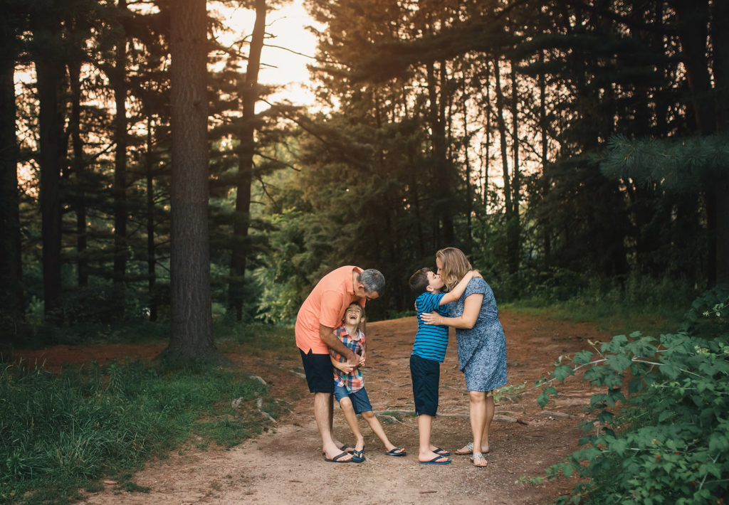 family hugging and laughing on path tall trees