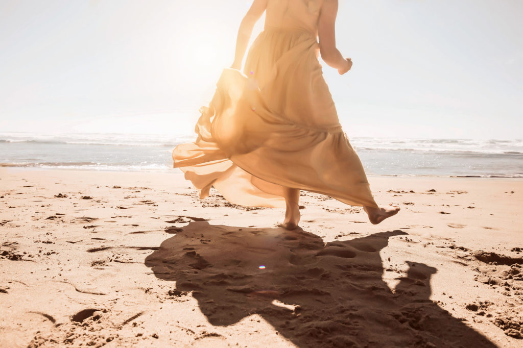 girl dancing on beach in yellow dress