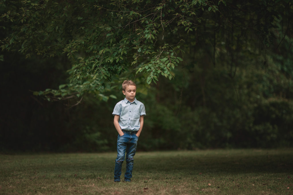 boy standing under tree hands in pockets