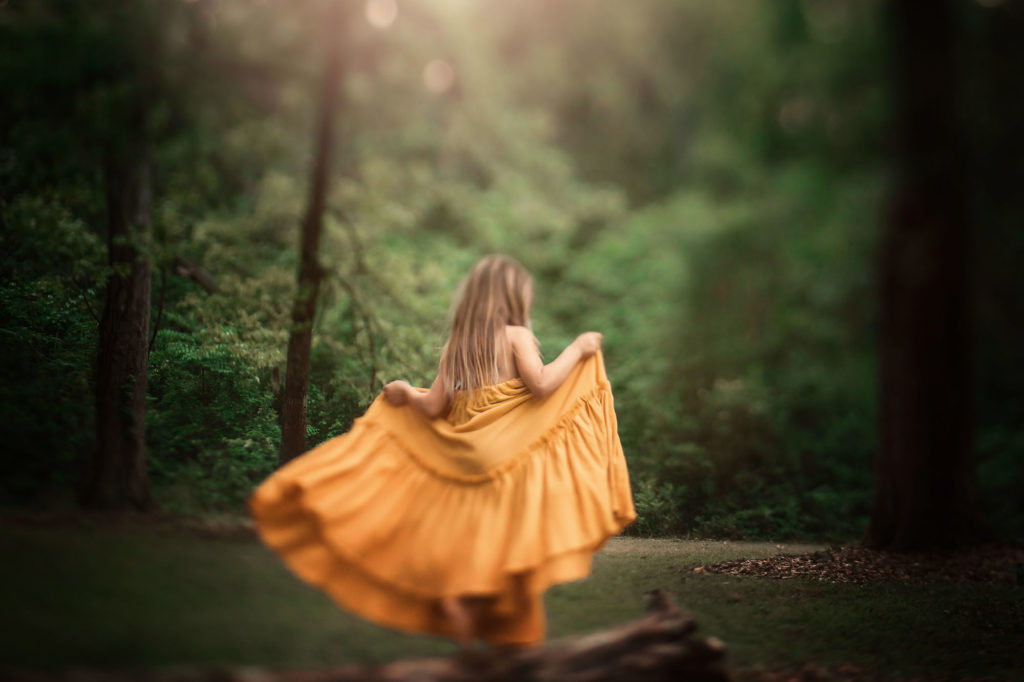 girl walking along log with yellow dress