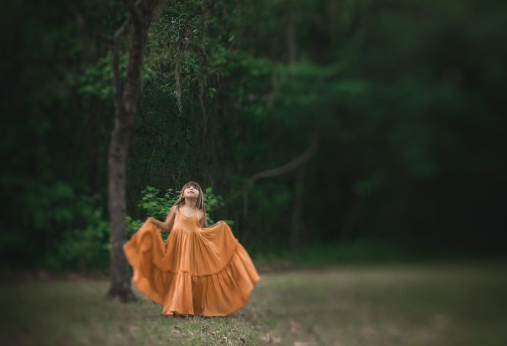 girl in yellow dress looking up to tree