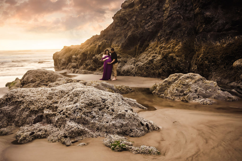 couple by rocks at beach maternity portrait