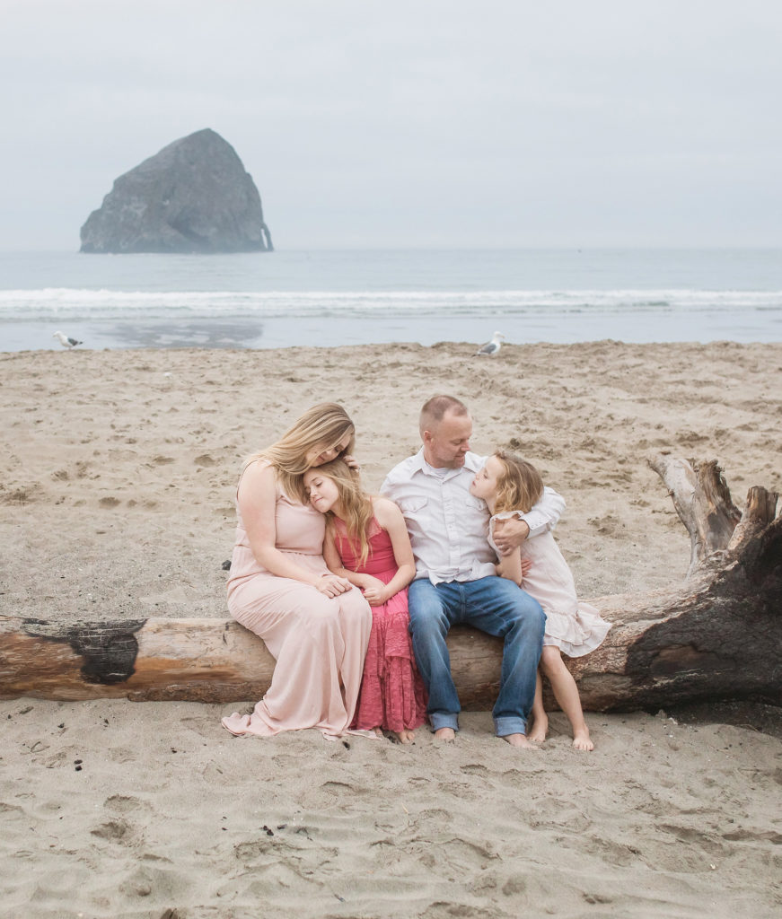 family sitting on driftwood oregon
