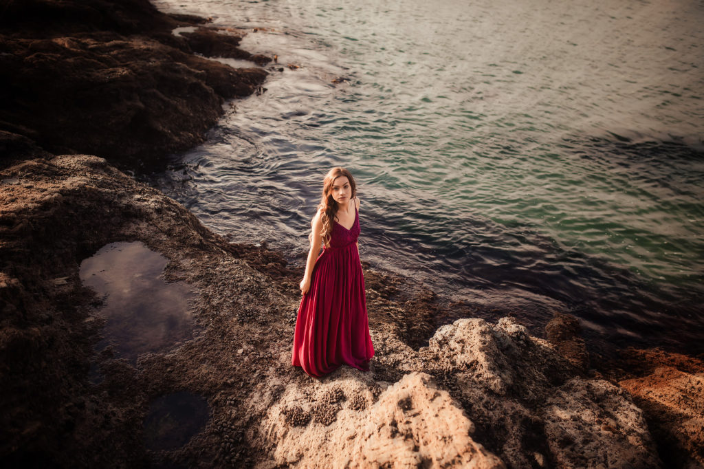 girl in red dress standing by water