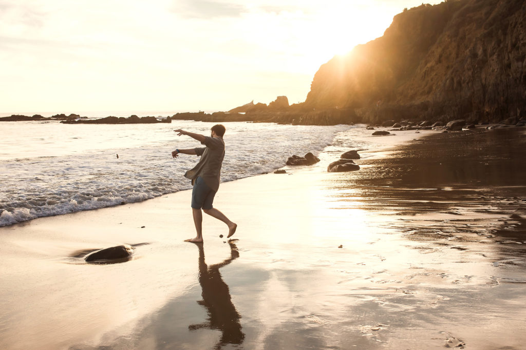 teenage boy throwing rocks into ocean