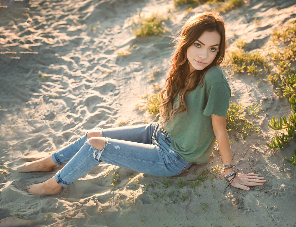 girl in green shirt sitting in sand