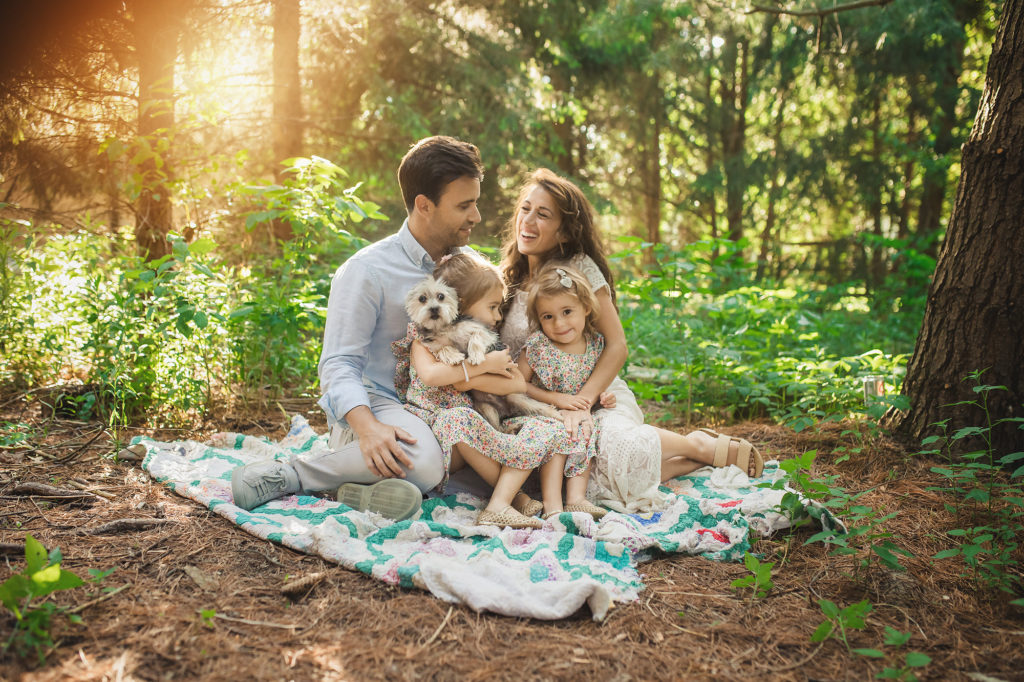 family of four with dog in woods on blanket