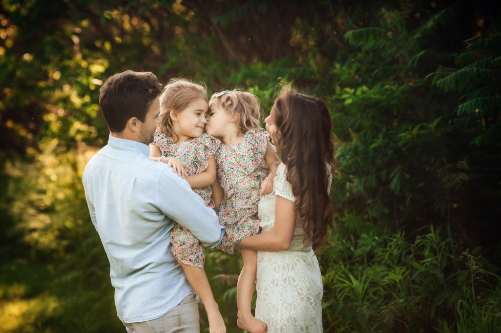 family with two sisters kissing outdoor
