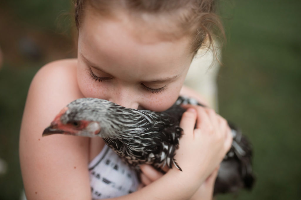 girl snuggling black and white chicken