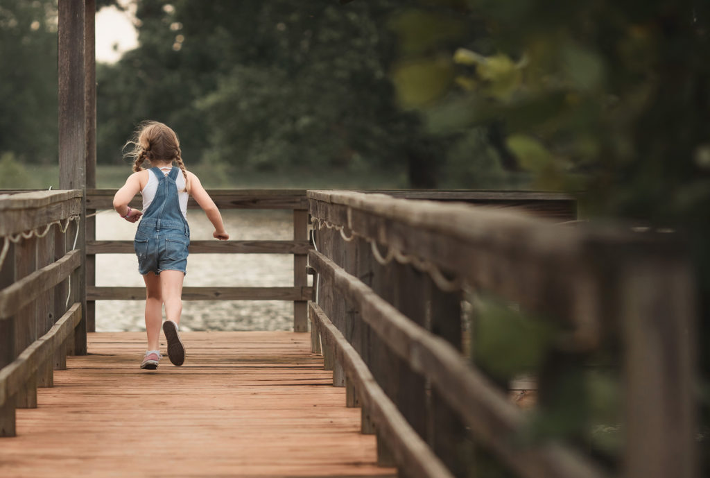 girl running along dock in overalls