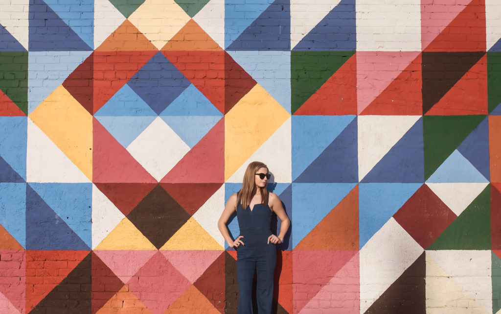 girl in sunglasses by colorful geometric wall